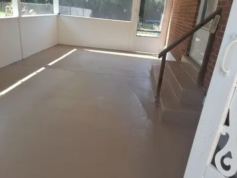 Enclosed porch with a gray floor, a brick wall and steps
