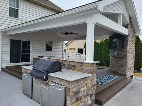 Outdoor kitchen with a stone base, grill and stainless doors under a covered patio