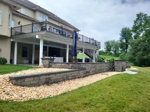 Two tiers of capped block retaining wall with river stone, below a raised deck