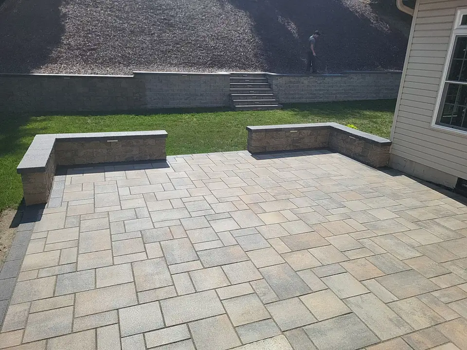 Paver patio with two seat walls and a block retaining wall with steps behind it