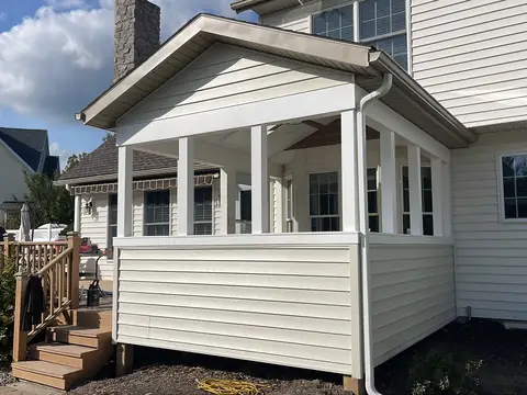 Enclosed porch with a gable roof, white windows and vinyl siding