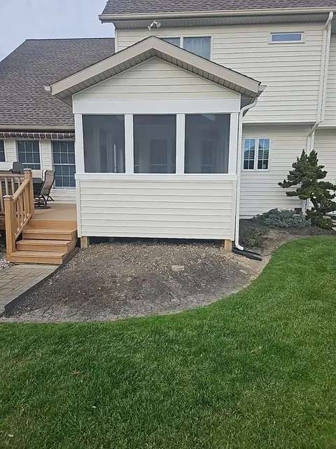 Enclosed porch on a deck with wood stairs, rear view
