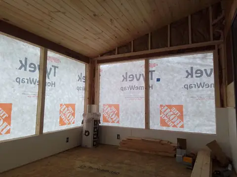 Sunroom framing with a pine ceiling, house wrap and window openings