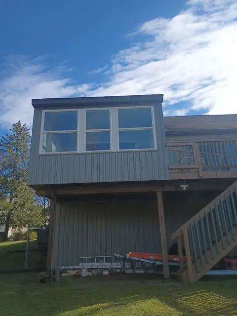 Sunroom on posts above a deck, with a row of windows