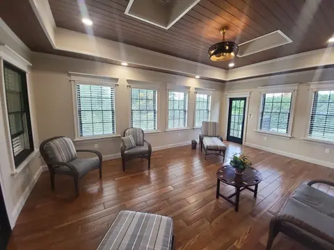 Sunroom interior with a wood plank ceiling, a hardwood floor and windows