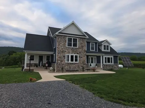Two-story custom home with a stone front, navy siding and a covered porch