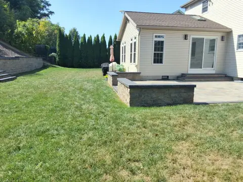 Home addition with a sliding door onto a paver patio with a seat wall
