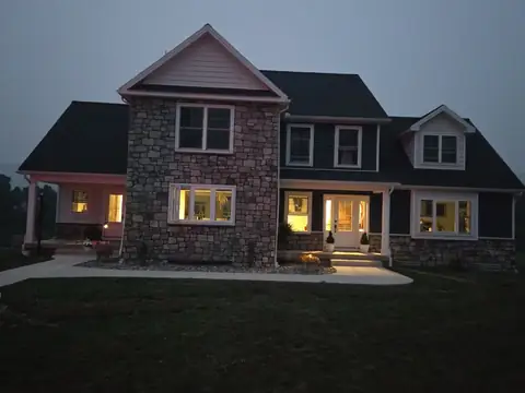 Two-story home with a stone front at dusk, its windows lit