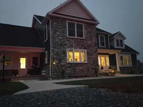 New home with a stone front and a covered porch at dusk