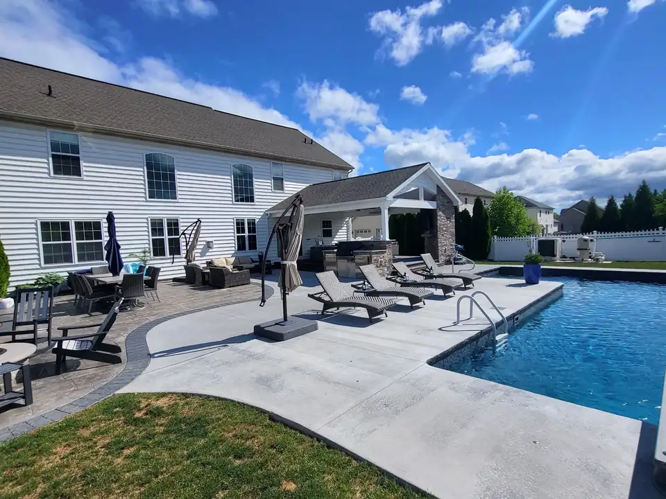 Covered patio beside a concrete pool deck