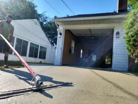 Concrete driveway pour from the truck chute, wet concrete at the garage