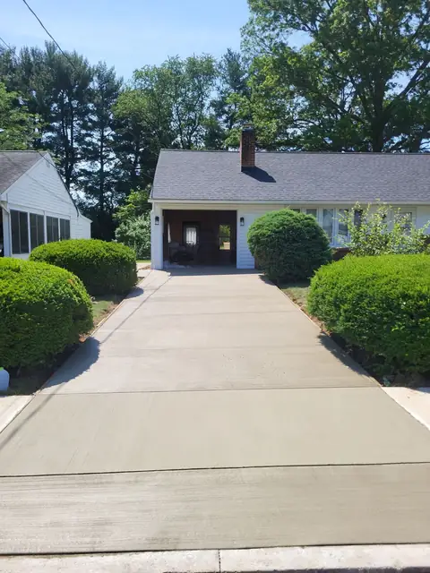 Broom-finished concrete driveway with control joints, leading to a garage