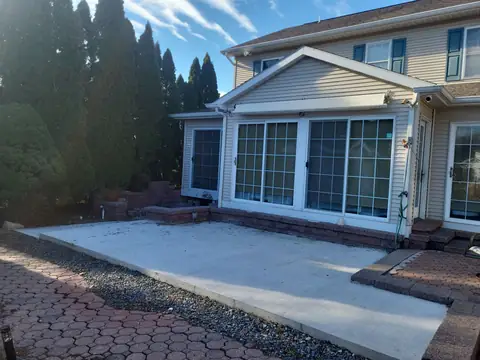 New concrete patio slab beside a sunroom, with a paver border