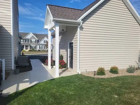 Concrete walkway to a covered entry portico beside a garage