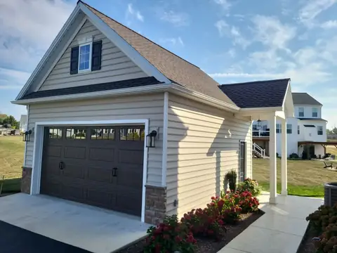 Detached garage with stone wainscot and a covered side porch