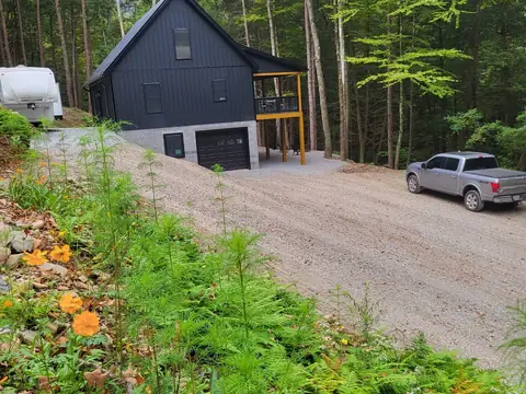 Gravel drive through a wooded lot to a board-and-batten building