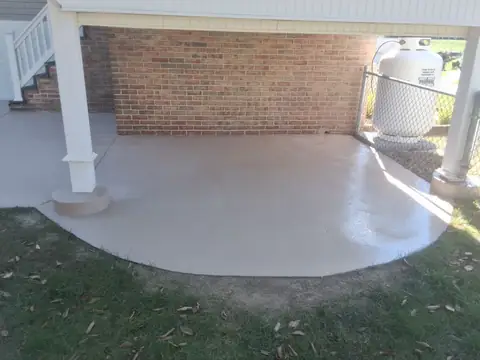 Curved tan concrete patio by a white deck post