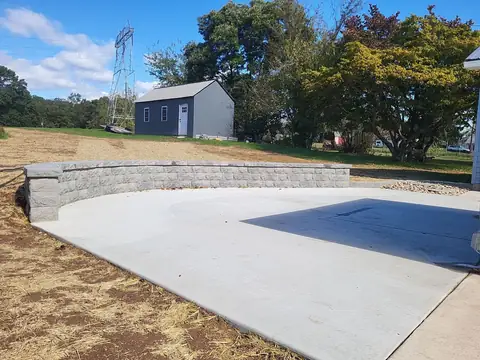 Concrete patio with a curved block seat wall in a backyard