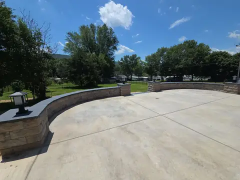 Large concrete patio bordered by a curved block seat wall in a backyard