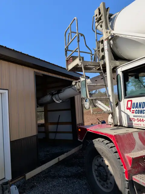 Concrete truck chute pouring a pole barn floor