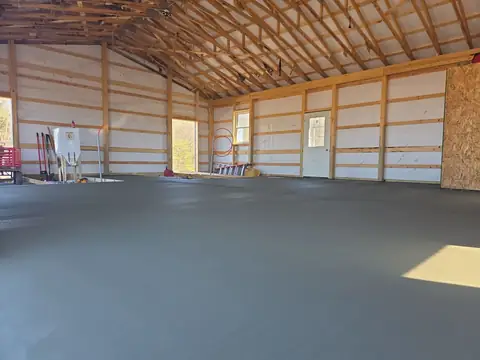Fresh concrete slab inside a pole barn, wide view