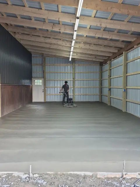 Crew finishing a concrete slab inside a pole barn