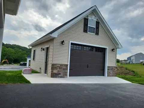 Detached garage with stone wainscot and a gable window