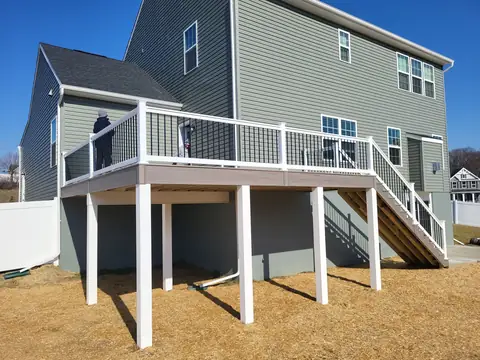 Second-story deck with white railing, black balusters and stairs