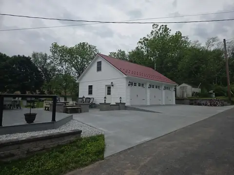 Concrete patio and driveway beside a three-car garage