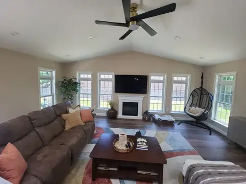 Family room addition with a fireplace, windows and a ceiling fan