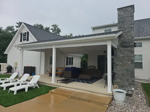 Covered patio beside a tall stone chimney