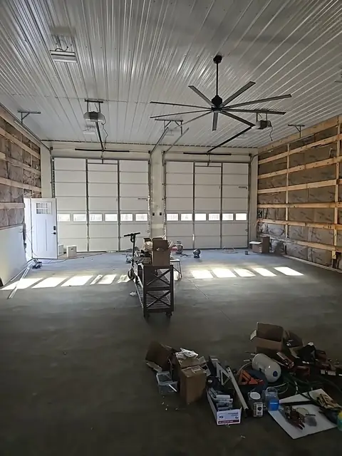 Pole barn interior with a concrete floor, ceiling fans and overhead doors