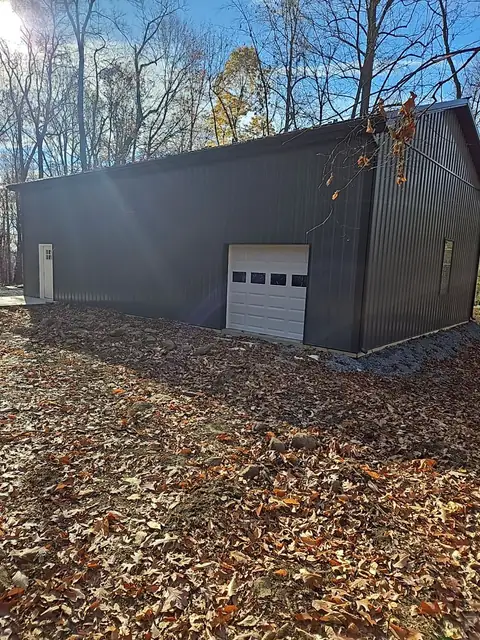 Pole barn side entry door and overhead door on a wooded lot