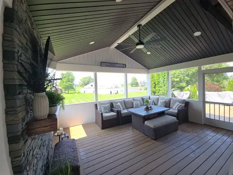 Screened porch interior with seating and a ceiling fan