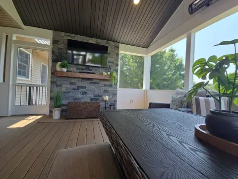 Screened porch interior with a fireplace, a TV and a table