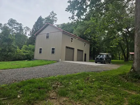 Two-story garage with two doors and metal siding, on a gravel drive