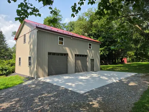 Pole building garage with a red metal roof and a concrete apron