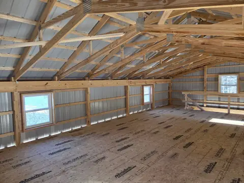 Pole barn loft interior with wood trusses and windows