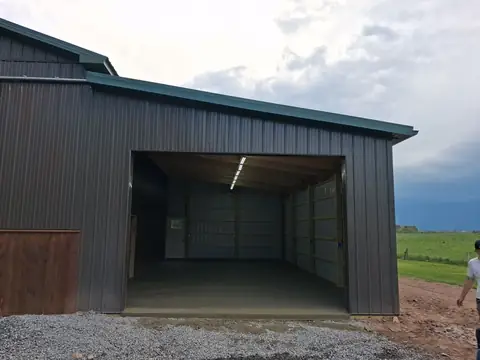 Dark steel pole barn with a wide open bay and a concrete floor