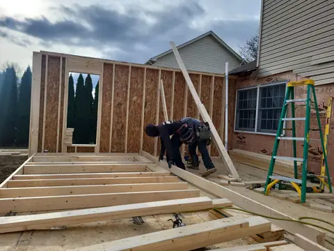 Crew raising wall framing on an addition
